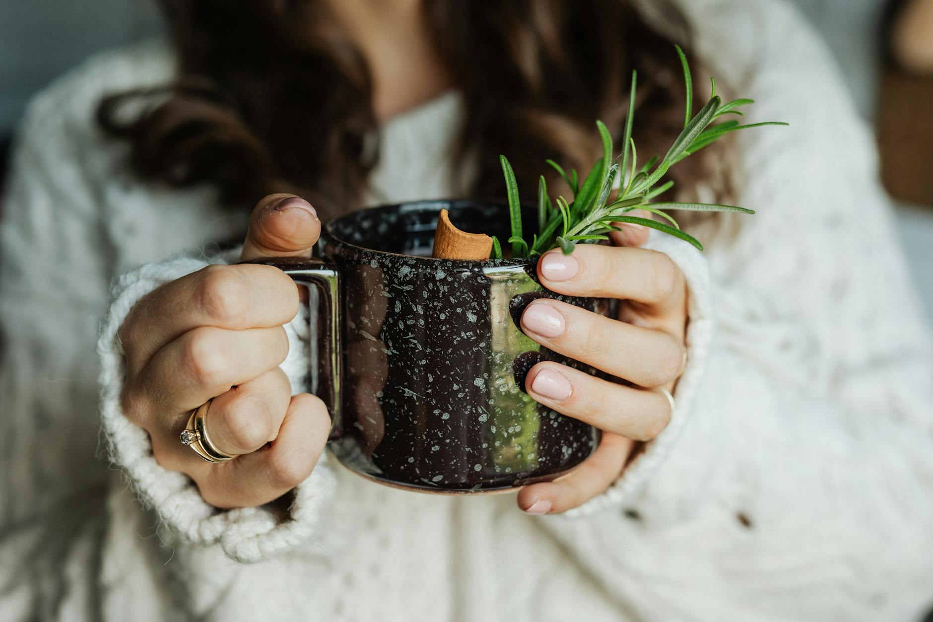 A woman in a warm sweater holding a herbal tea mug, perfect for autumn days.